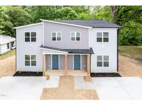 Modern two-story duplex features a gray facade, blue doors, and well-manicured landscaping at 1047 |1049 E Harnett St, Dunn, NC 28334
