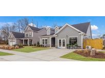 A view of the two-story home with gray siding, dormers, well-manicured lawns, and a concrete driveway at 153 Tennyson Dr # 235, Garner, NC 27529