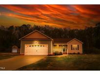 Charming single-story home with an attached garage and manicured lawn under a dramatic sunset sky at 40 Patricia S Vann Ct, Dunn, NC 28334