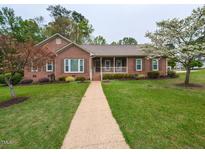 Charming brick home featuring a manicured lawn, inviting front porch, and beautiful landscaping at 422 Old Scarborough Ln, Garner, NC 27529