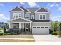 Charming two-story home featuring a well-manicured lawn and a two-car garage on a beautiful sunny day at 105 Smoky Emerald Way, Holly Springs, NC 27540