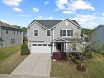 Charming two-story home featuring a two-car garage and manicured landscaping with a young tree in the front yard at 109 Oak Rise Ln, Fuquay Varina, NC 27526