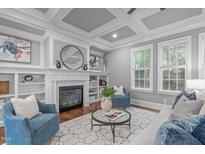 Bright living room featuring a cozy fireplace, built-in shelves, and coffered ceiling at 1104 Hobson Ct, Raleigh, NC 27607