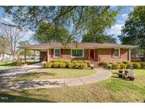Charming brick home featuring a manicured front yard, walkway, and a convenient attached carport at 1108 Friendly Rd, Dunn, NC 28334