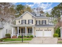 Charming yellow brick two-story home with black shutters, a covered front porch, and an attached two-car garage at 119 Faison Rd, Chapel Hill, NC 27517