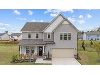 Charming two-story home featuring a manicured lawn, attached two-car garage, and a welcoming front porch at 2157 Blue Iris Way, Zebulon, NC 27597