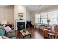 Cozy living room boasts a fireplace, hardwood floors, and lots of natural light from bright windows at 4712 Bright Pebble Ct, Raleigh, NC 27604