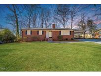 Charming brick ranch-style home featuring a well-manicured front yard and a convenient carport at 5013 Green Oak Dr, Durham, NC 27712