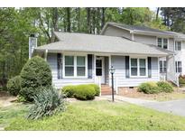 Charming townhome with blue siding, black shutters, landscaped lawn and brick steps at 6417 Meadow View Dr, Raleigh, NC 27609