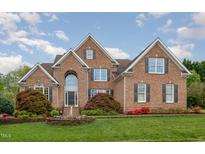 Traditional brick home with a manicured lawn, fountain, and beautiful landscaping at 9201 Club Hill Dr, Raleigh, NC 27617