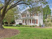 Charming two-story home features a welcoming front porch, red shutters, attached garage, and lush lawn at 1008 Brittley Way, Apex, NC 27502