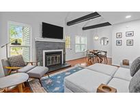 Bright living room features a stone fireplace, TV, a blue rug and hardwood flooring at 102 Choptank Ct # B5, Cary, NC 27513