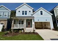 Charming two-story home with light blue siding, front porch, a two-car garage and landscaped front yard at 1237 Porters Call Dr, Wendell, NC 27591