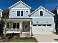 Charming two-story home with pale blue siding, white trim, a pink front door and attached two-car garage at 1237 Porters Call Dr, Wendell, NC 27591