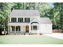Charming white two-story home boasts a welcoming front porch and well-manicured lawn at 1326 Apache Ln, Apex, NC 27502