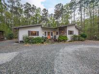 Charming single-story home featuring stone accents, gravel driveway, and lush landscaping at 1604 Meadow Ln, Chapel Hill, NC 27516