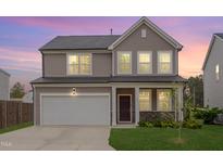 Charming two-story home with a two-car garage, stone accents, and a well-manicured lawn during a lovely dusk at 205 Loxton St, Fuquay Varina, NC 27526