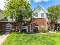 Charming townhouse featuring a brick facade, arched windows, and well-maintained lawn at 2101 Piney Brook Rd # 105, Raleigh, NC 27614