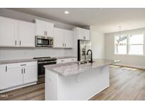 Bright kitchen with white cabinetry, granite countertops, stainless appliances, and a large island at 520 Folk Song Way, Wendell, NC 27591