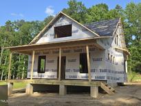 New home under construction featuring a covered porch and a glimpse of the surrounding wooded area at 608 Hemlock Ave, Durham, NC 27707