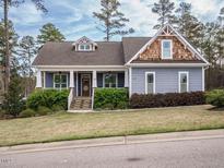 Charming home featuring a landscaped front yard and welcoming covered porch with stone accents on the columns at 110 Streamside Dr, Sanford, NC 27330