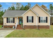 Charming single-story home with light yellow siding, black shutters, and well-manicured lawn at 114 Carriage Hill Dr, Stem, NC 27581