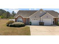 Charming home featuring a brick facade, grey siding, well-kept landscaping, and a two-car garage at 123 Ariel St, Lillington, NC 27546
