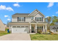 Charming two-story home with a manicured lawn, attached garage, and covered porch at 1725 Langlais Dr, Graham, NC 27253