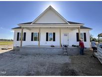 New construction home featuring white siding, black shutters, and a welcoming front porch with exposed pillars at 2895 Bakers Chapel Rd, Smithfield, NC 27577