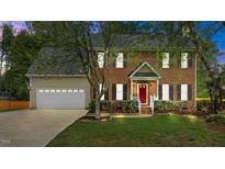 Charming two-story brick home with a well-manicured lawn, red front door, and attached two-car garage at 3517 Boren Ct, Raleigh, NC 27616