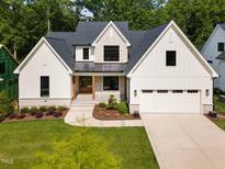 Stunning two-story home featuring a white exterior, stone accents, and a well-manicured lawn at 3832 Noremac Dr, Raleigh, NC 27612