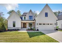 Beautiful white modern farmhouse with stone accents and a well-manicured front lawn at 3832 Noremac Dr, Raleigh, NC 27612