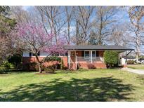 Charming brick home featuring a cozy front porch and a lovely flowering tree in the front yard at 5033 Green Oak Dr, Durham, NC 27712