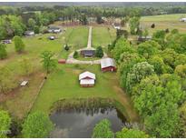 Expansive property featuring a pond and multiple outbuildings surrounded by lush greenery at 5069 Cokesbury Rd, Fuquay Varina, NC 27526