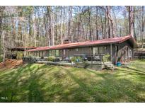 Long, ranch-style home with a rusty metal roof and a large, inviting deck in a wooded setting at 518 Morgan Creek Rd, Chapel Hill, NC 27517