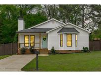 Charming white cottage-style home featuring a cozy porch and well-manicured lawn at 120 Cabrita Ct, Holly Springs, NC 27540