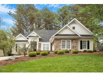 Charming home with a stone facade, manicured lawn and mature trees at 1537 Heritage Club Ave, Wake Forest, NC 27587