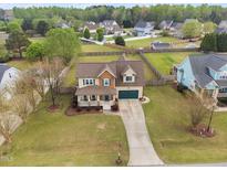 Charming two-story home with a well-manicured lawn, front porch, and an attached two-car garage at 2113 Conroy Way, Willow Springs, NC 27592