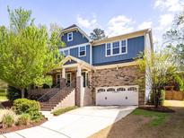 Charming two-story home featuring a brick and blue exterior with a two-car garage and manicured front yard at 2125 Toad Hollow Trl, Apex, NC 27502