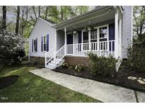 Charming home featuring a welcoming front porch with white railings and blooming flowers at 300 Round About Rd, Holly Springs, NC 27540