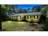 Charming single-story home with a classic design, black shutters, and mature trees on a well-manicured lawn at 310 Edward Ln, Louisburg, NC 27549