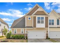 Inviting townhouse featuring a two-car garage and neutral colored siding against a bright blue sky at 318 Acorn Hollow Pl, Durham, NC 27703