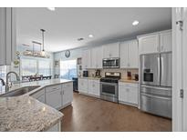 Well-lit kitchen featuring white cabinets, stainless steel appliances, and a dining area at 405 Club Center Dr, Youngsville, NC 27596