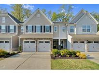 Charming townhome featuring stone accents, a two-car garage, and manicured landscaping at 425 Summit Trail Dr, Hillsborough, NC 27278