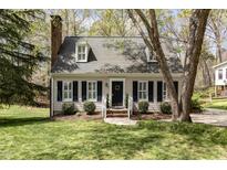 Charming two-story home features a brick chimney, dormer windows, and landscaped yard with fresh green grass at 520 Tall Oaks Dr, Durham, NC 27713