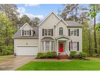 Charming two-story home featuring a bright red front door, well-manicured lawn, and attached two-car garage at 5405 Whisperwood Dr, Durham, NC 27713