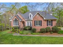 Charming red brick home with a lush green lawn and manicured landscaping at 5900 Orchid Valley Rd, Raleigh, NC 27613