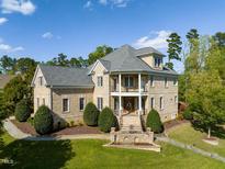 Stately brick home featuring manicured landscaping, a covered front porch, and a classic architectural design at 642 Bear Tree Creek, Chapel Hill, NC 27517