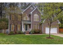 Beautiful two-story brick home with a manicured lawn, attached garage, and lush trees at 8 Queensland Ct, Durham, NC 27712