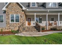 Charming front entrance featuring stone accents, wood door, and rocking chairs on the inviting front porch at 9026 Privette Hill Ln, Spring Hope, NC 27882